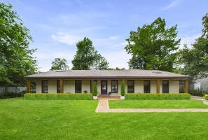 Elegant single-story home with a spacious lawn and covered front porch in Lafayette, LA