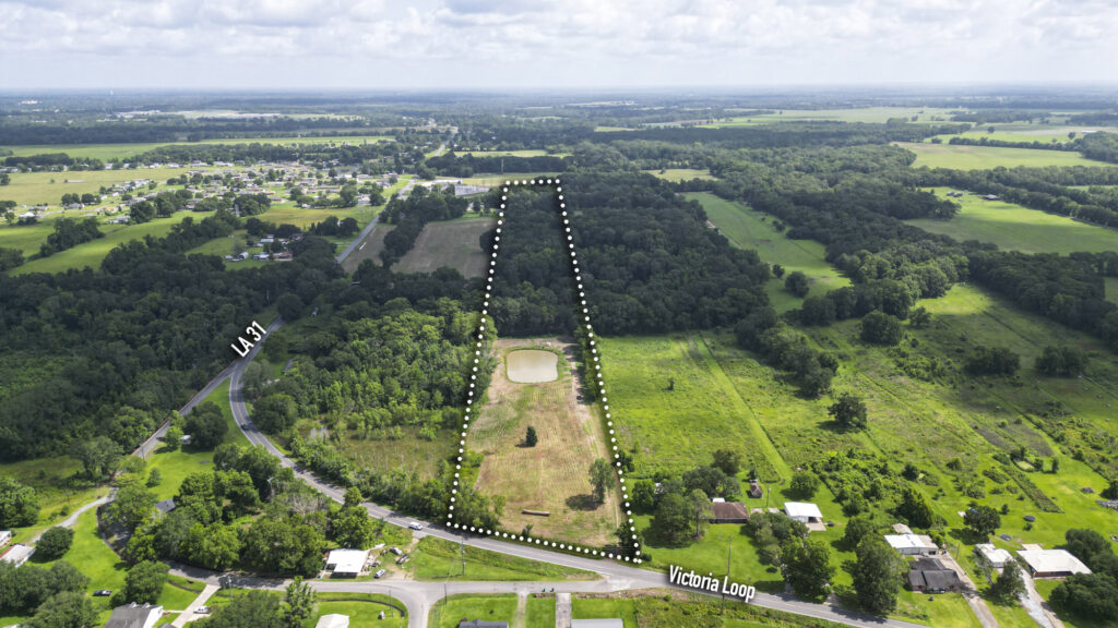 Aerial view of an 11-acre tract of land for sale on Victoria Loop in Opelousas, LA. The outlined property shows a large private pond, a cleared front section, and a mature hardwood forest at the rear.